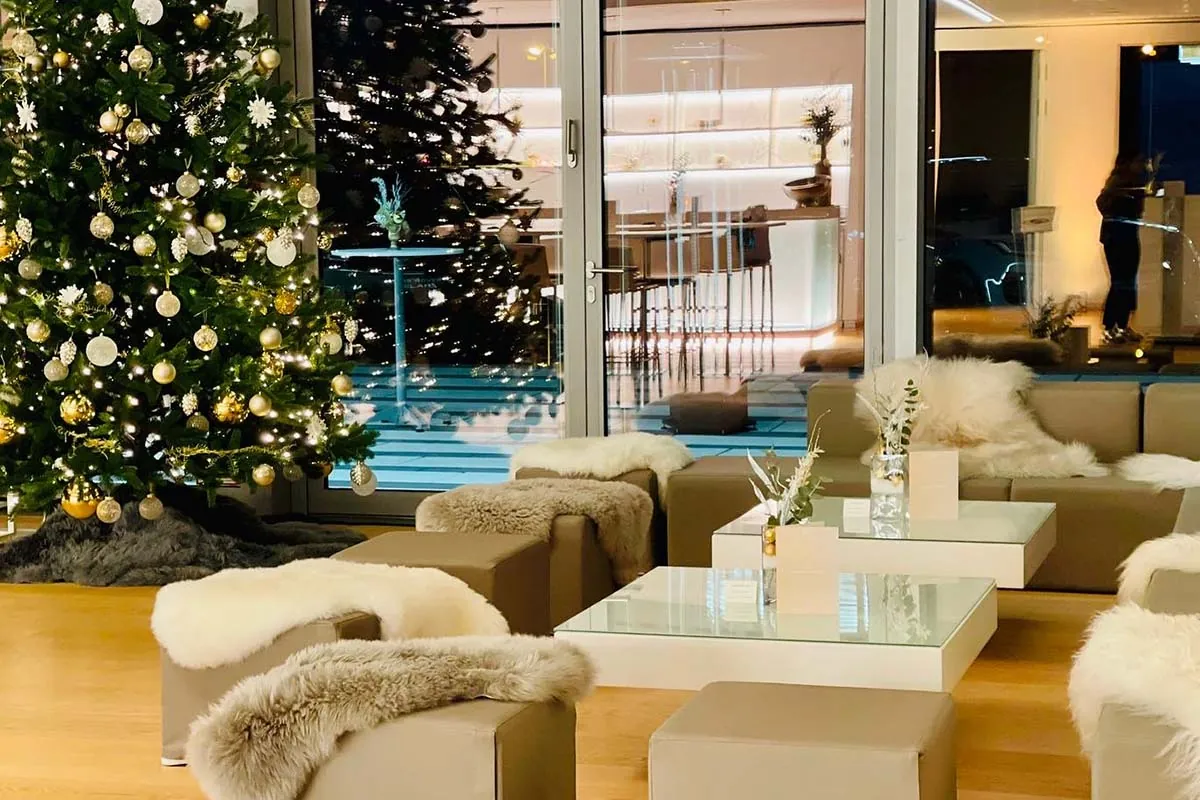 Lounge mit goldenem Weihnachtsbaum und Fellen auf hellen Sitzwürfeln