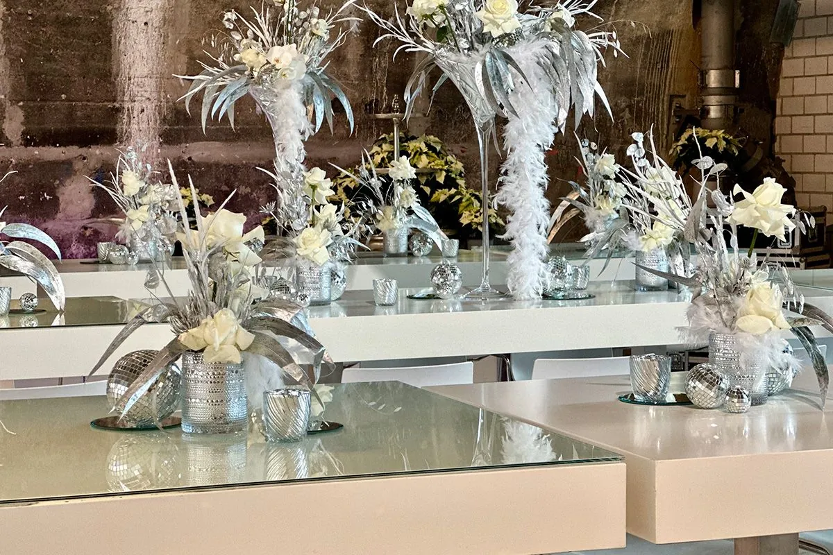 Weiß-silbern eingedeckte Tafel mit Rosen und Federn von ELEMENTS Catering