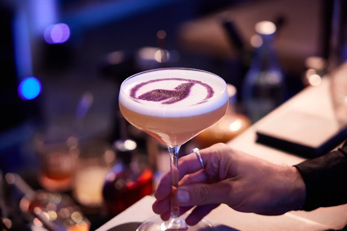 Barkeeper serviert einen Cocktail mit Motiv im Schaum