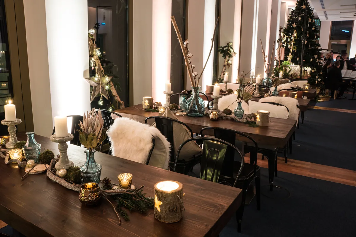 Lange Holztafel mit Kerzen, Fellen und Weihnachtsbaum an der Fensterfront