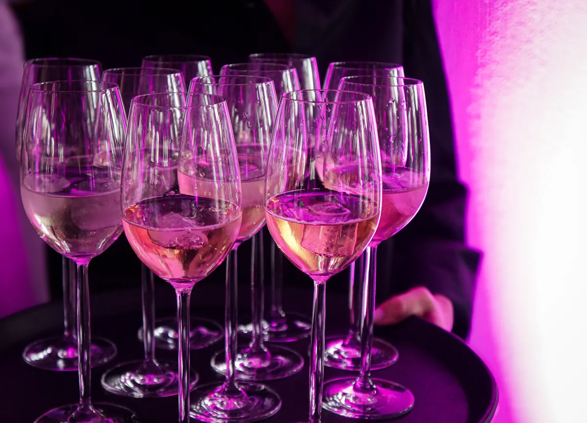 Tablett mit Weißweingläsern im pinken Licht